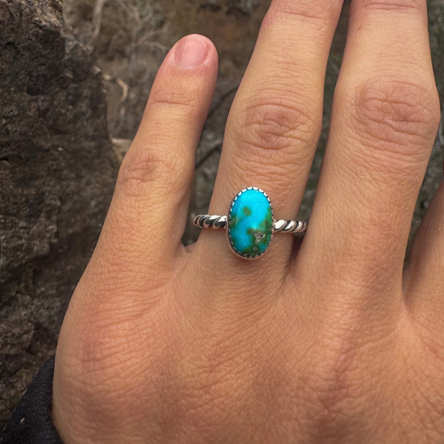 Turquoise ring on a person's finger with a natural background