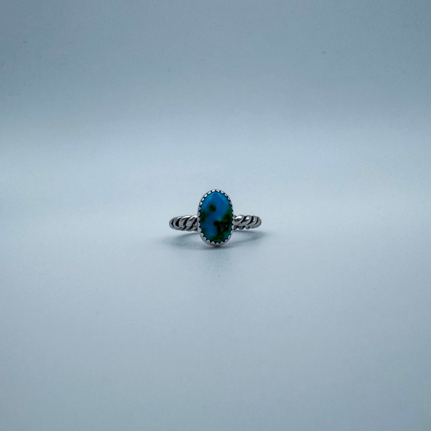 Silver ring with a blue and green turquoise gemstone on a white gray background