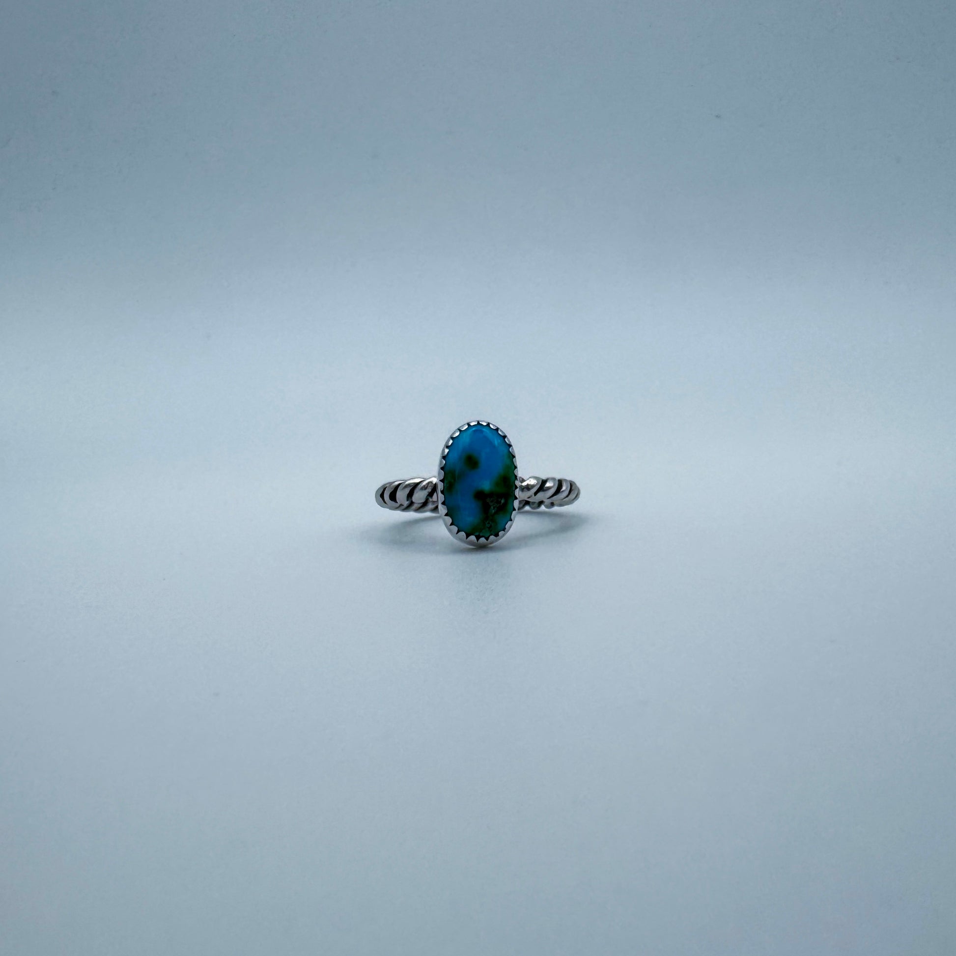Silver ring with a blue and green turquoise gemstone on a white gray background