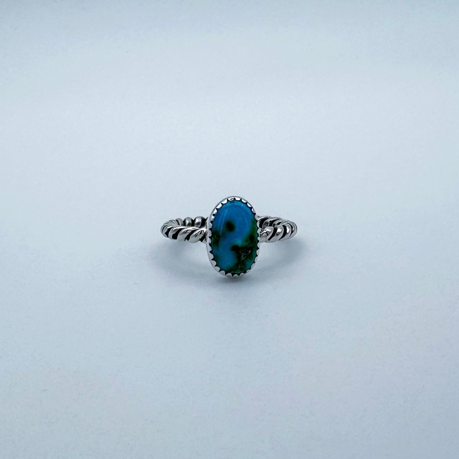 Silver ring with a blue turquoise gemstone on a light white background