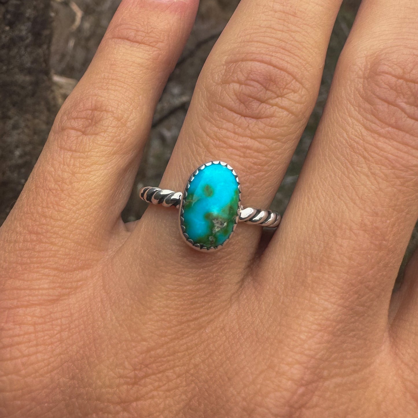 Turquoise ring on a person's finger with a blurred background