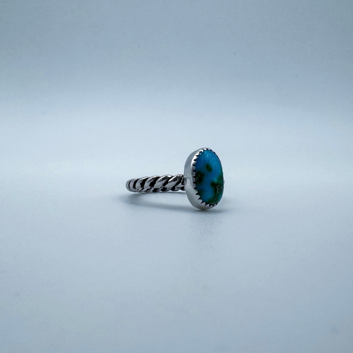 Silver ring with a blue turquoise gemstone on a light white background